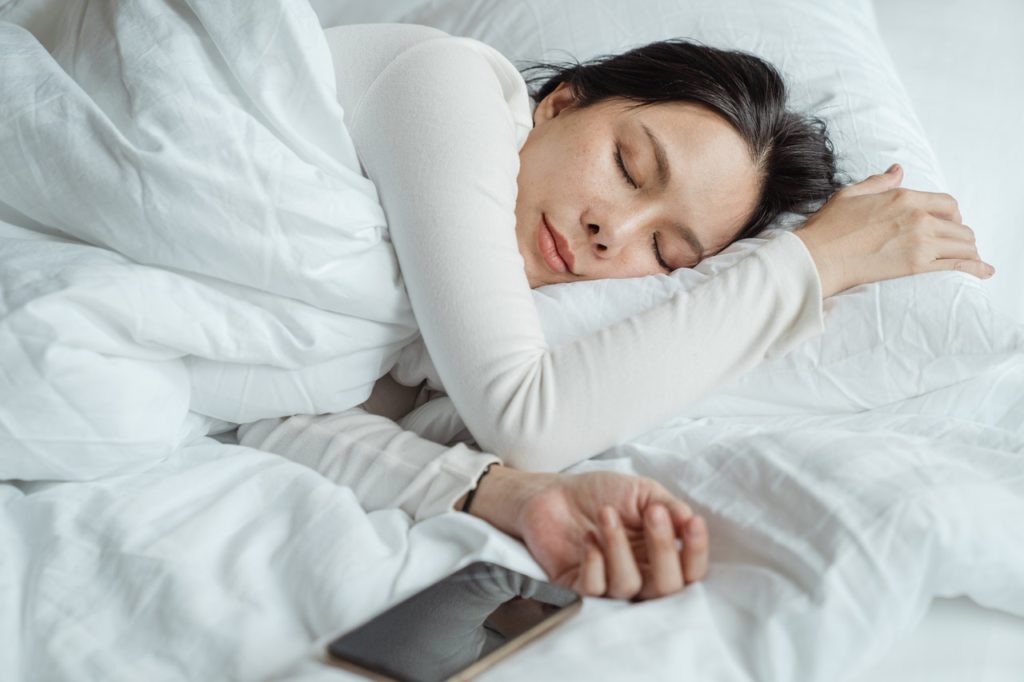 woman sleeping peacefully on side in white bed