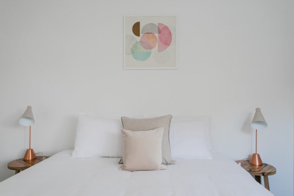 white bedding with modern lights and artwork above bed