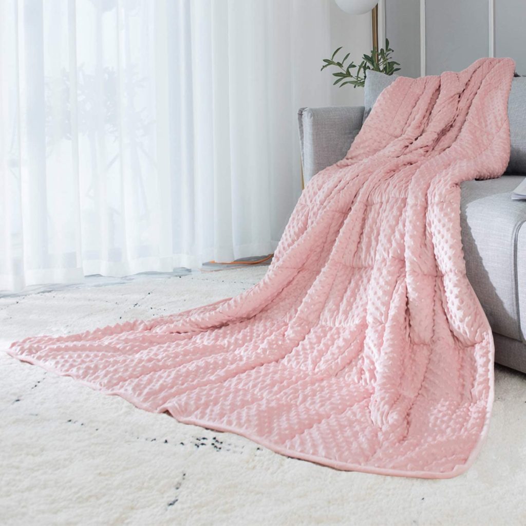 pink weighted blanket draped over couch