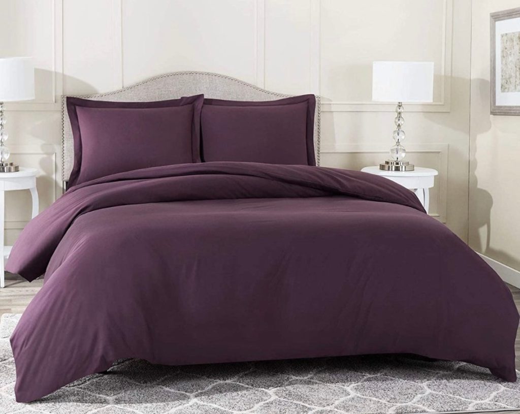 purple comforter on bed in clean room