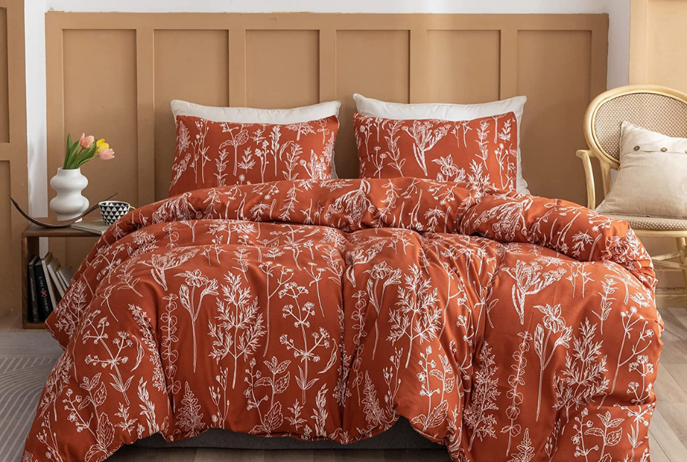 rust orange comforter with white botanical print on bed