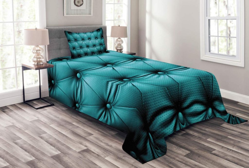 stylized teal comforter on bed in clean modern room
