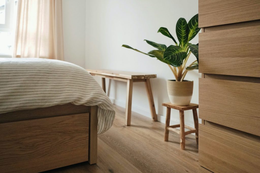 corner of bedroom with light wood furniture and plant on bench