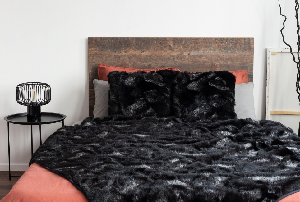 trendy bed with black faux fur blanket