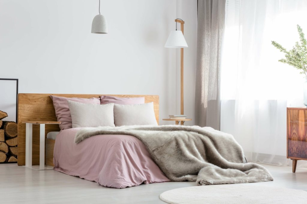 trendy bedroom with pink bedding and a plush grey throw blanket