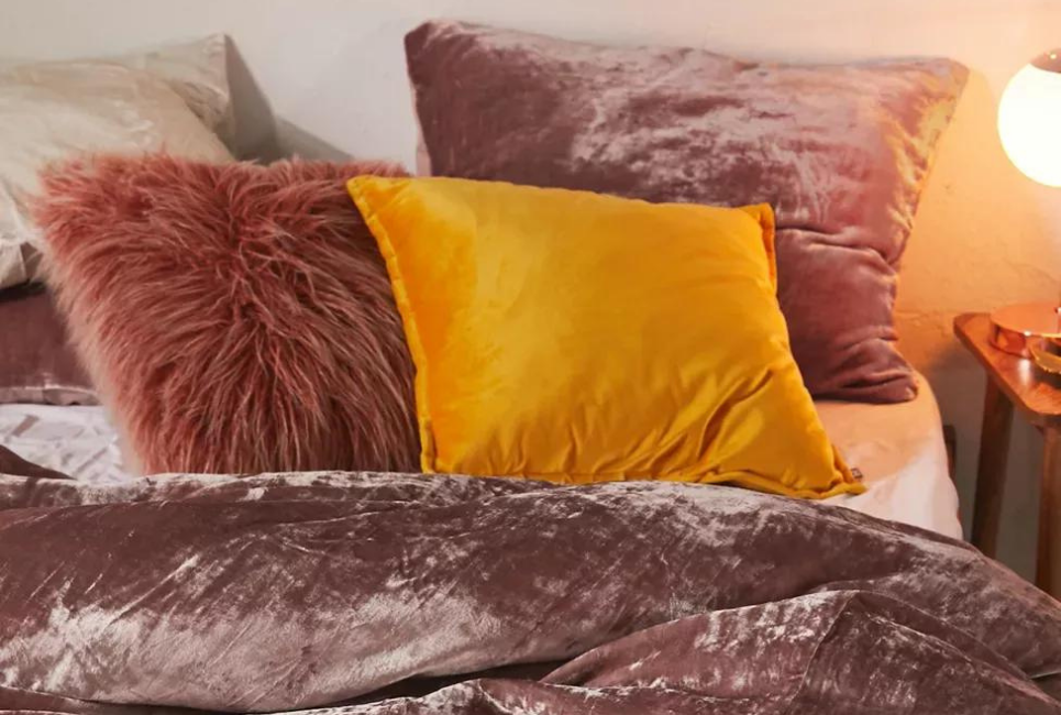 trendy dusty rose velvet comforter on bed with orange pillow