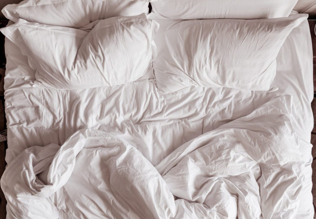 unmade bed with white bedding