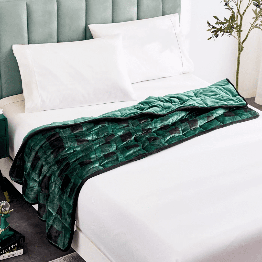 white bed and pillows with green decorative throw blanket