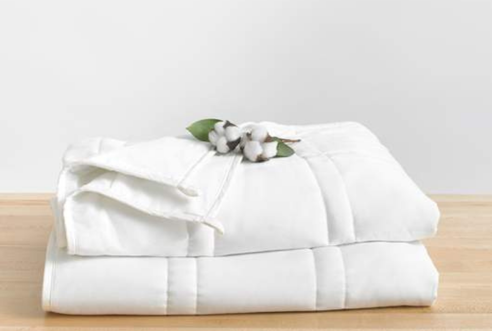 white blanket folded with cotton plant resting on top