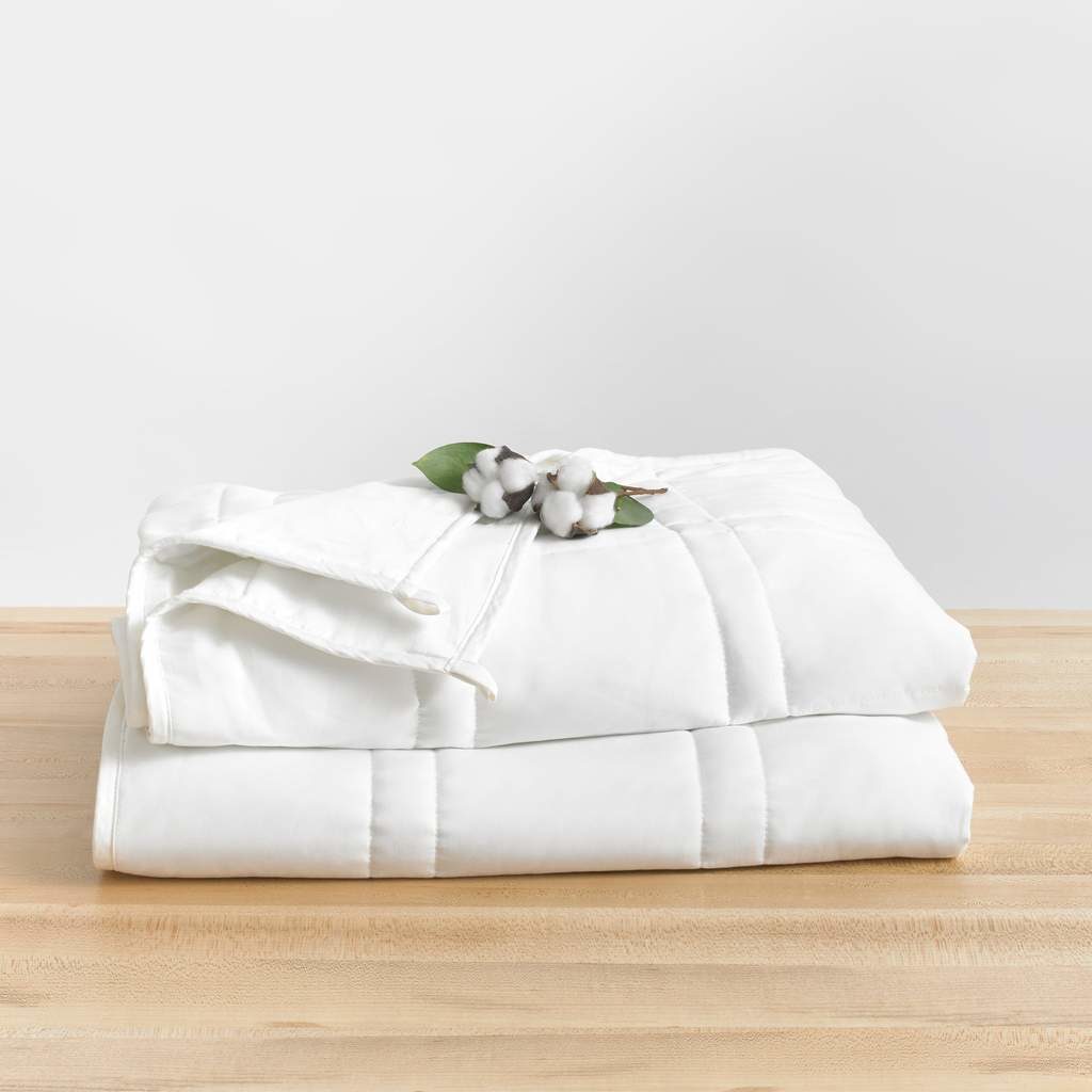 white blanket neatly folded with cotton plant resting on top