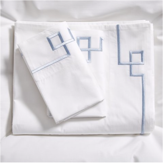 white sheet set with blue geometric embroidery