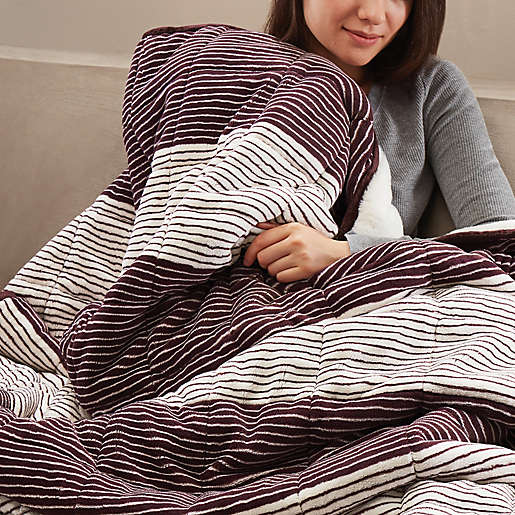 woman holding up a striped black and white blanket over herself