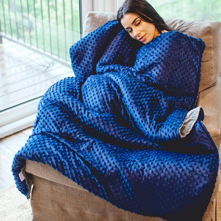 woman lounging on chair under blue soft blanket