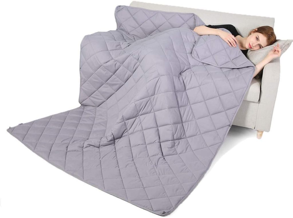 woman lounging on couch with grey weighted blanket over her