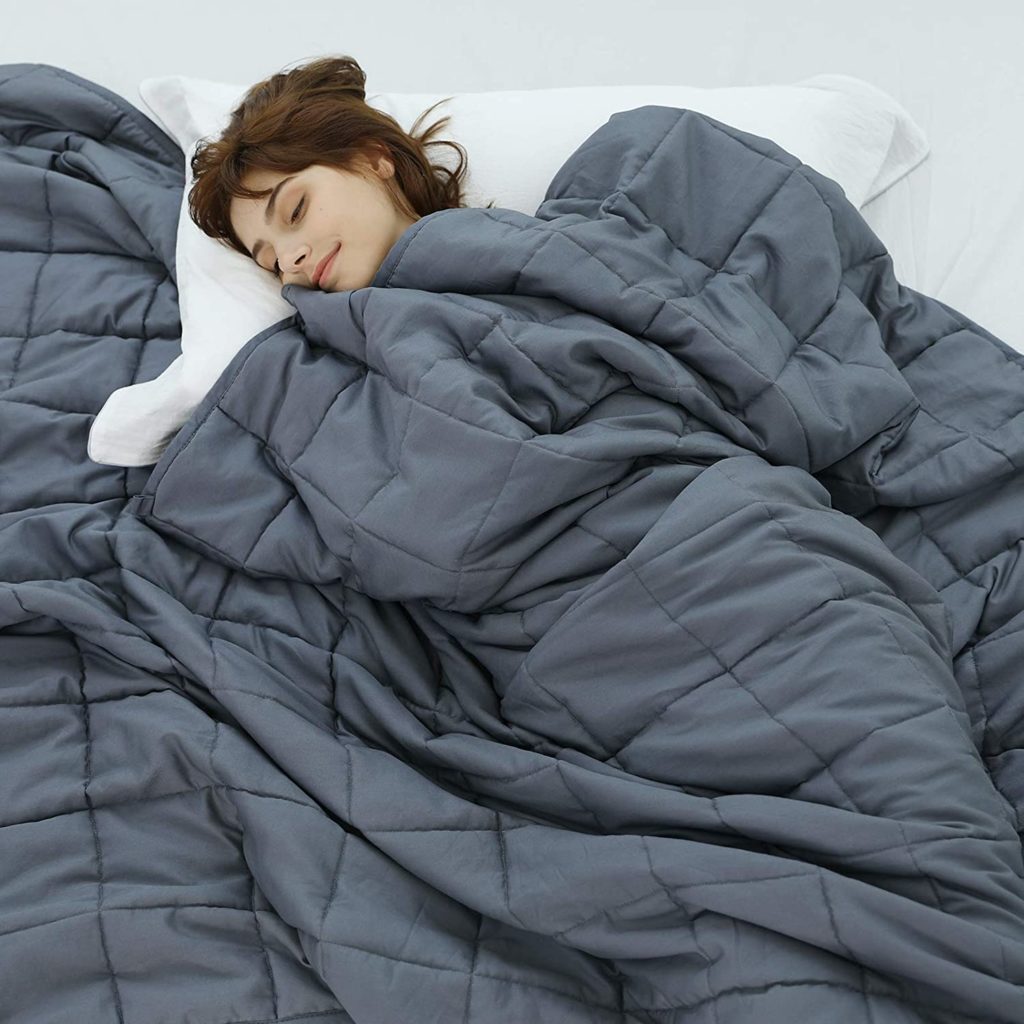 woman sleeping peacefully in bed with grey blanket over her