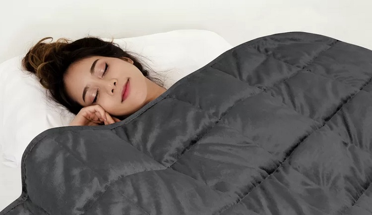 woman sleeping peacefully under dark grey weighted blanket