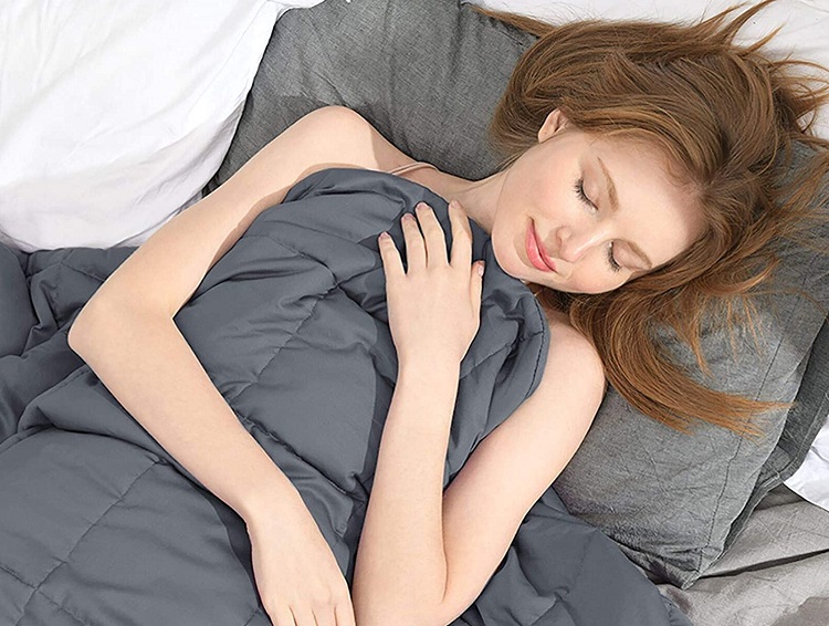 woman sleeping peacefully under grey weighted blanket 1