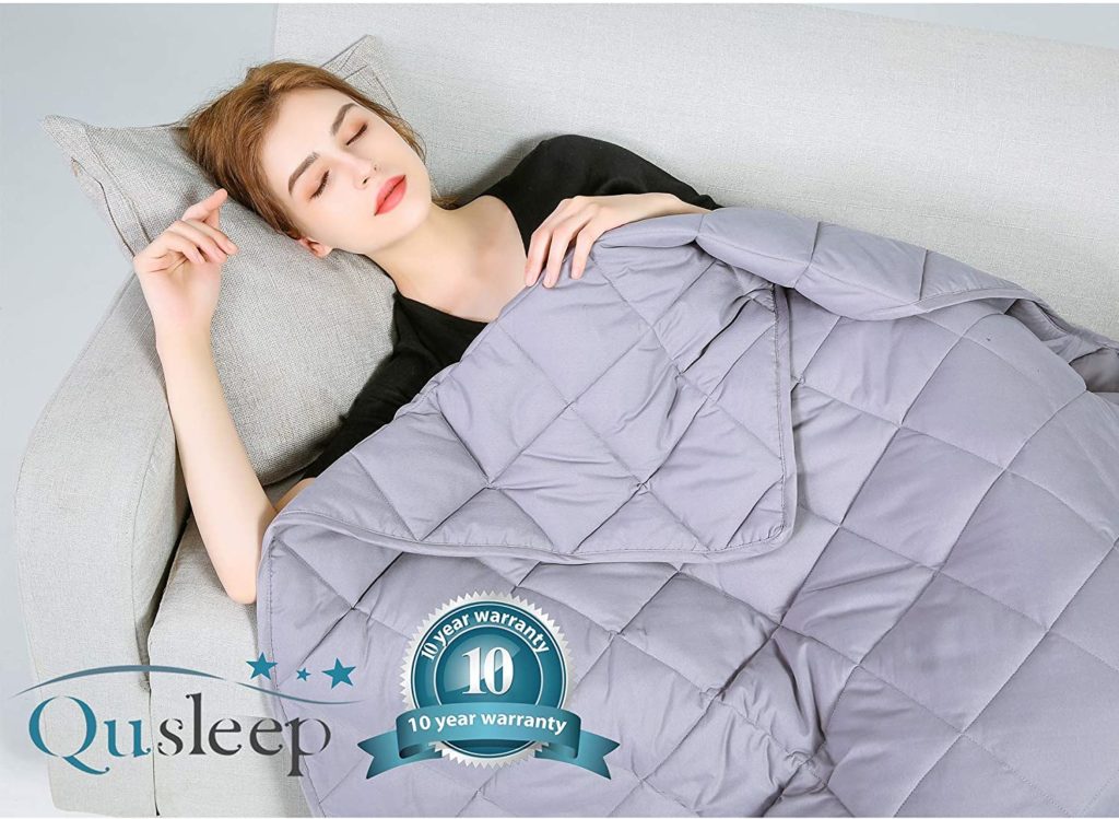 woman sleeping peacefully under lavender weighted blanket with QuSleep logo