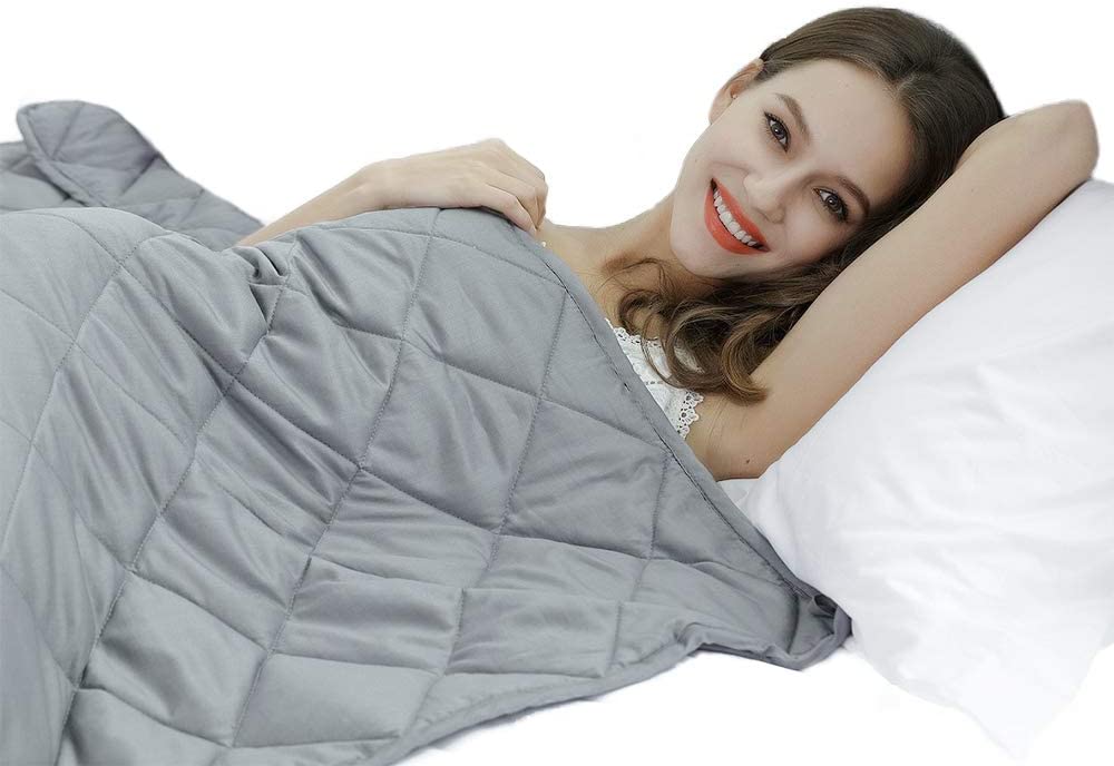woman smiling laying down with grey blanket over her