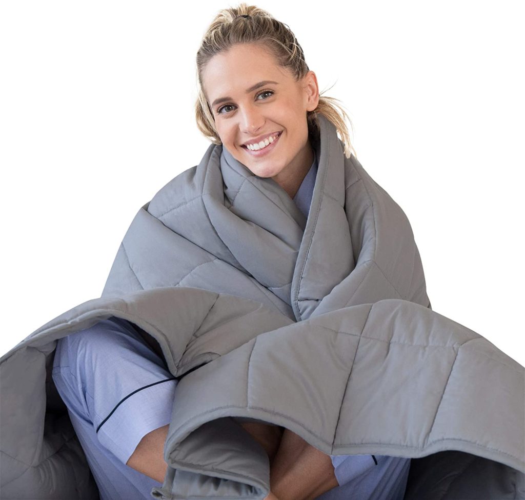 woman smiling wrapped up in grey blanket