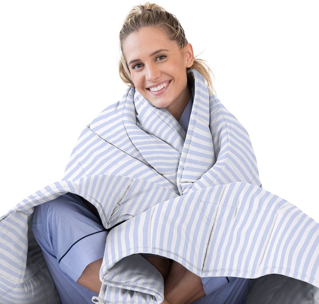 woman smiling wrapping herself up in white and blue striped blanket