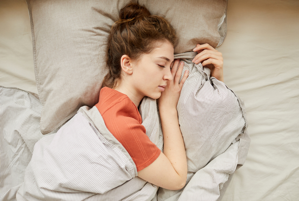 woman sleeping peacefully in bed with taupe bedding