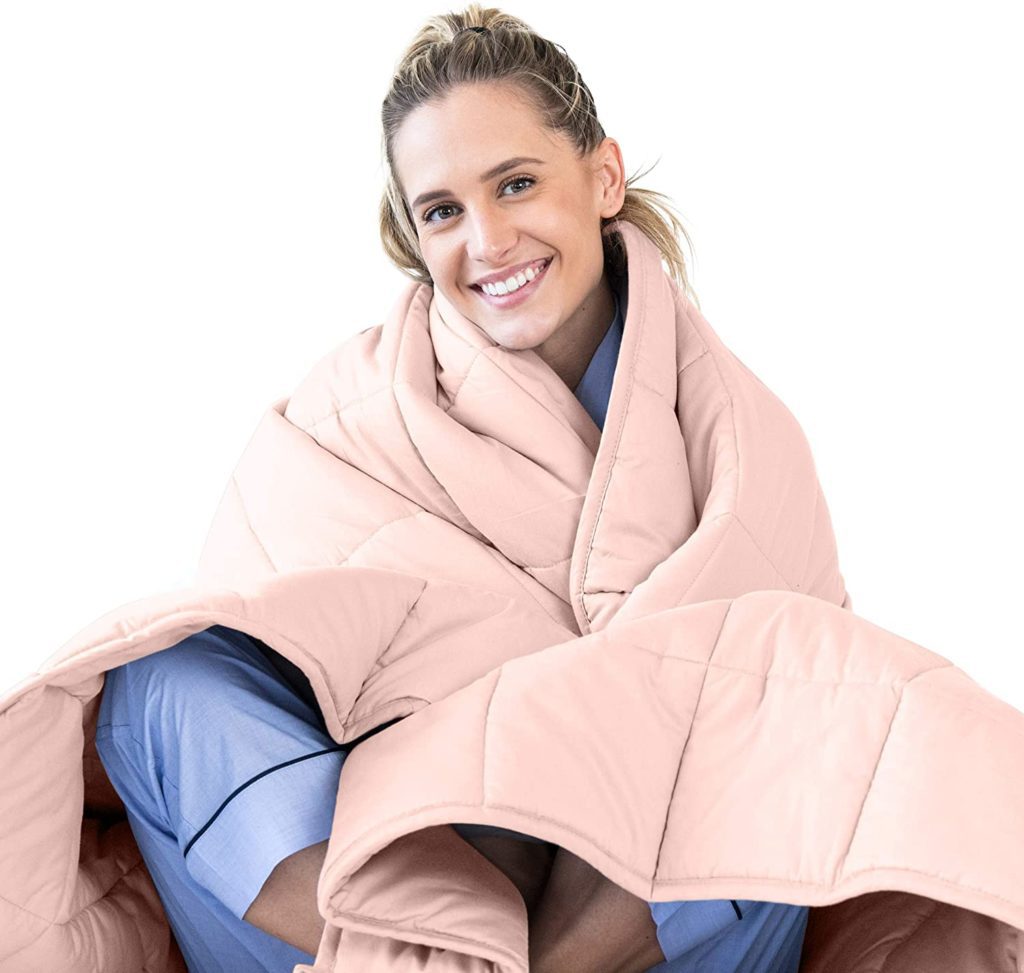 woman wrapping herself up in pink blanket and smiling