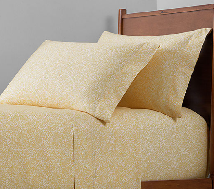 yellow and white patterned sheet and pillow on bed