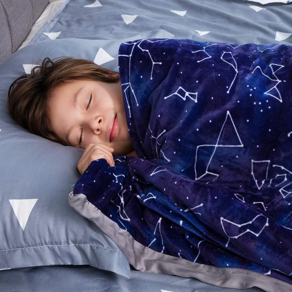 young boy sleeping peacefully under blue celestial print blanket
