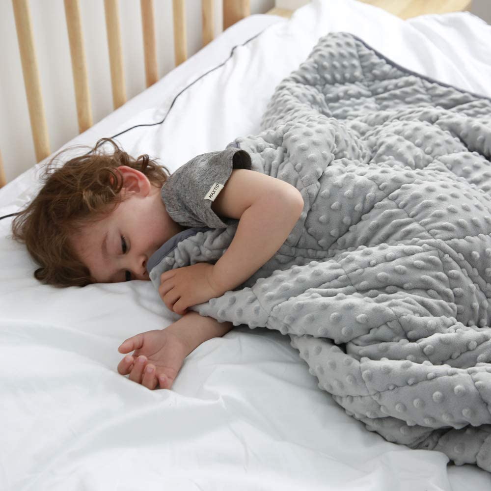 young child sleeping under grey weighted blanket