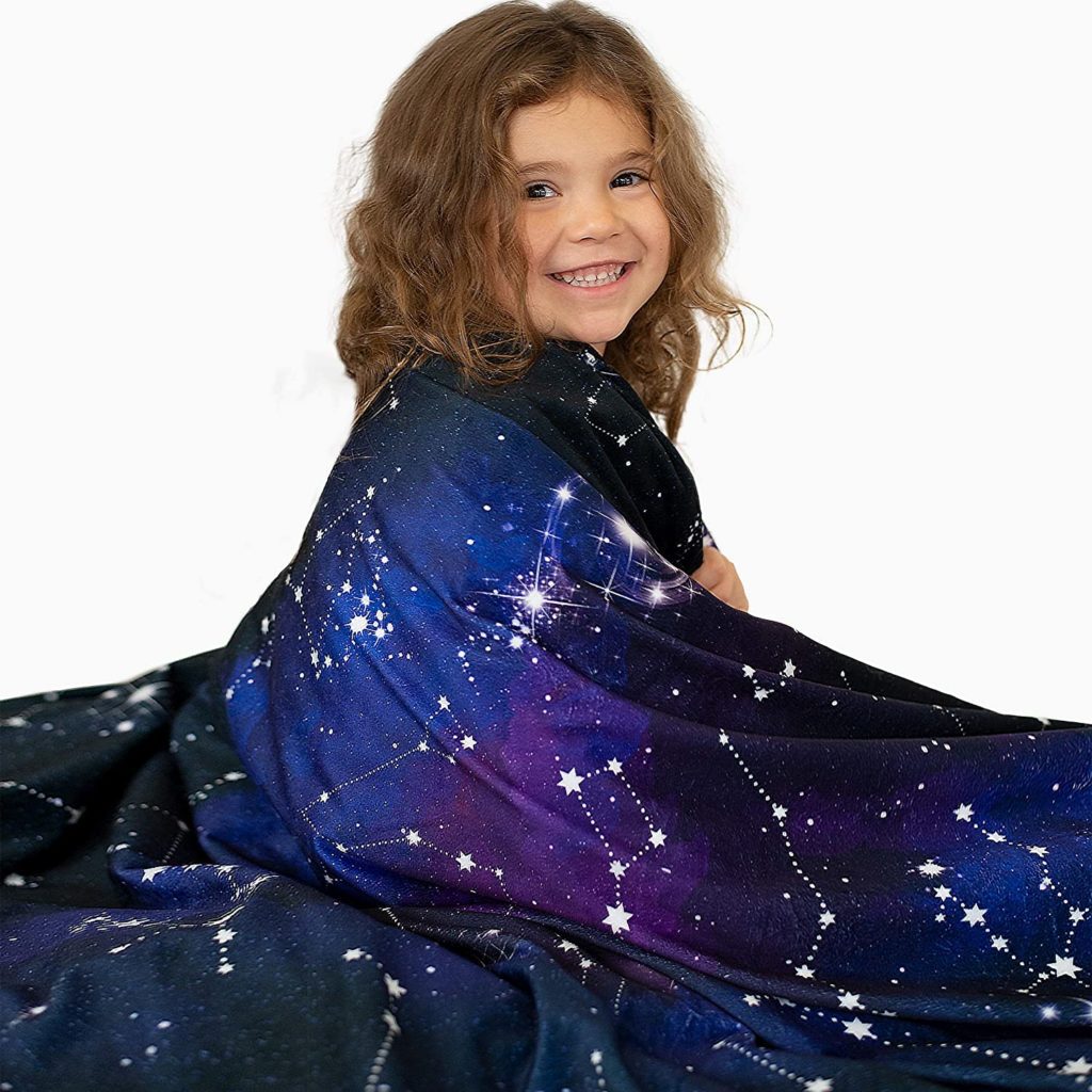 young child wrapped up in galaxy print blanket
