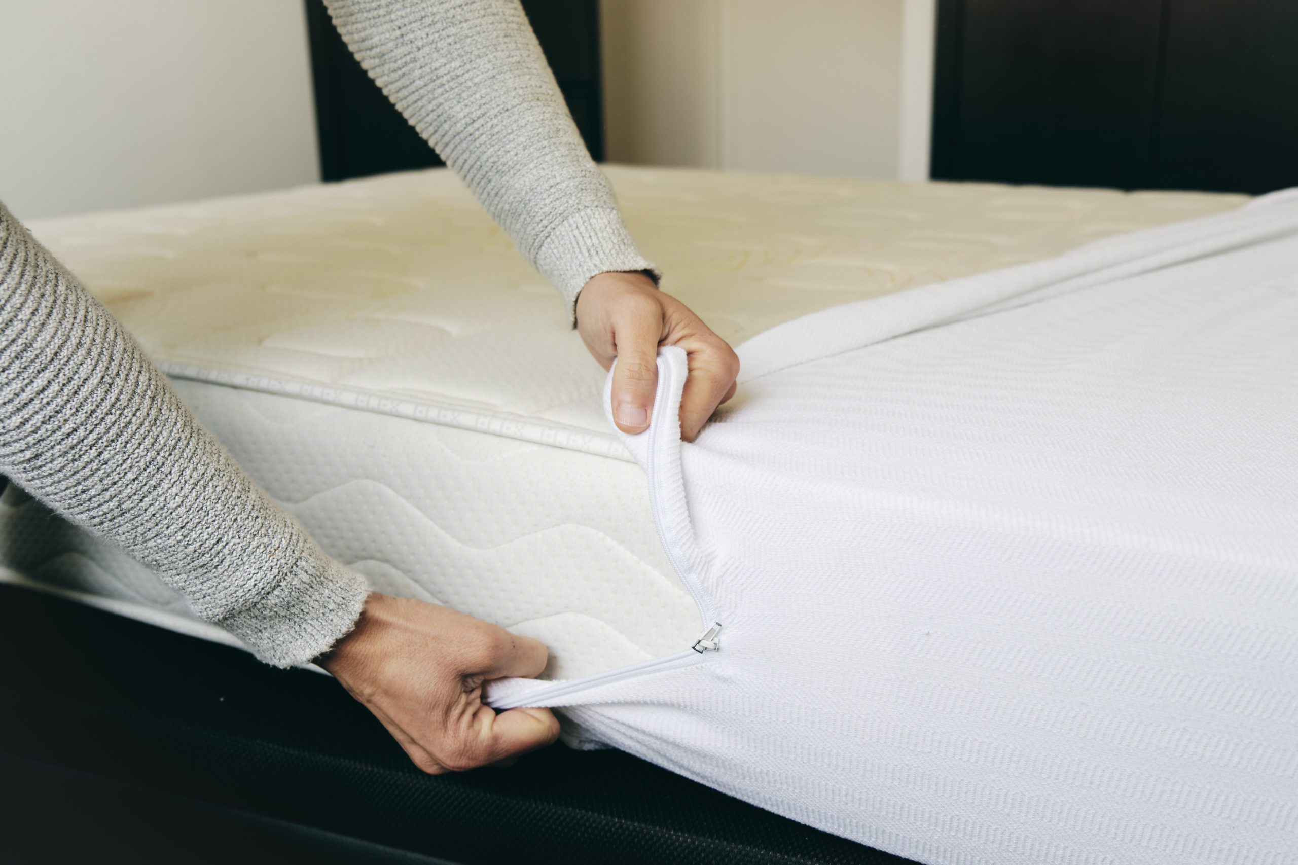 closeup of a young caucasian man covering a mattress with a white mattress protector