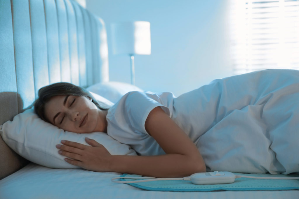 Young Woman Sleeping on Electric Heating Pad
